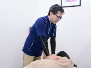 女性の背中を施術する整体師