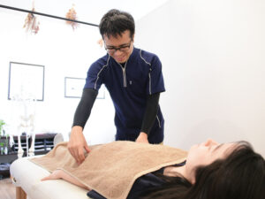 仰向けの施術を行う整体師