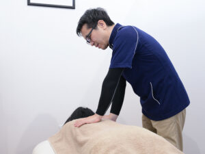 女性の背中を施術する整体師